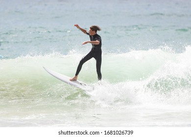 MANLY, NSW/AUSTRALIA – MARCH 2020: Young Adults Catching Waves Surfing At Manly Beach On A Bright Warm Sunny Day On Clear Blue Water