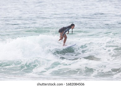 MANLY, NSW/AUSTRALIA – MARCH 2020: Young Woman Catching Waves Surfing At Manly Beach On A Bright Warm Sunny Day On Clear Blue Water