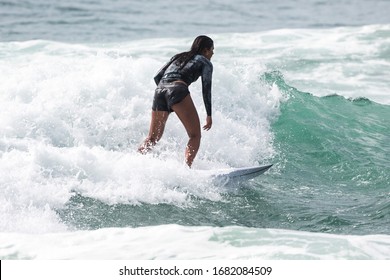 MANLY, NSW/AUSTRALIA – MARCH 2020: Young Woman Catching Waves Surfing At Manly Beach On A Bright Warm Sunny Day On Clear Blue Water