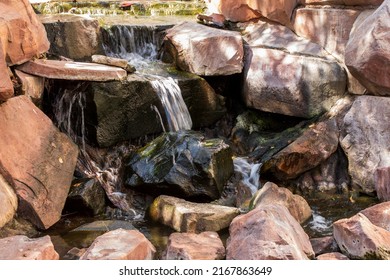  Manmade water fall with boulders and cascade.  Flowing water over rocks and boulders. 