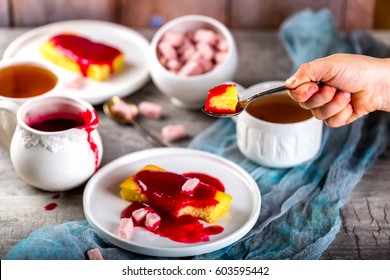 Manne Cake On A White Plate. Cake Drizzled With Raspberry Jam. The Tea Party. Children's Hand Holds The Spoon With A Piece Of Cake. Selective Focus