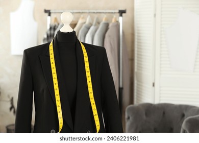 Mannequin with black jacket and measuring tape in tailor shop, space for text