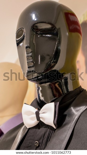 mannequin\
dressed in black suit and white bow\
tie.
