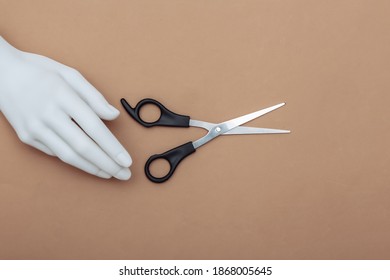 Mannequin Hand Holding Hair Scissors On Brown Background. Minimalism Beauty Concept