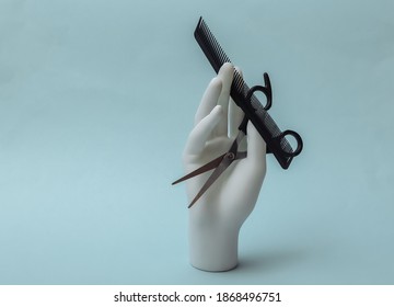 Mannequin Hand Holding Hair Scissors And Comb On Blue Background. Minimalism Beauty Concept