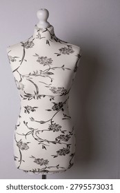 Mannequin on a white background with  patterned fabric upholstery. Fashion design concept showcasing textile choice, garment fitting, and creative studio work.