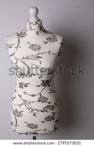 Mannequin on a white background with  patterned fabric upholstery. Fashion design concept showcasing textile choice, garment fitting, and creative studio work.