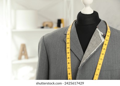 Mannequin with unfinished jacket and measuring tape in tailor shop, closeup. Space for text - Powered by Shutterstock