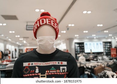 
Mannequin Wearing A Medical Mask In A Store. Ugly Christmas Sweater And Hat. New Year Excitement. Coronavirus Pandemic. 2021 New Normal.