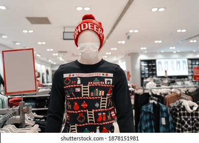 
Mannequin Wearing A Medical Mask In A Store. Ugly Christmas Sweater And Hat. New Year Excitement. Coronavirus Pandemic. 2021 New Normal.