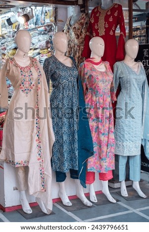 Mannequins wearing traditional Indian clothing in a storefront in the market. Salwar kameez, traditional North Indian women's attire. Colorful cotton dresses displayed for sale.