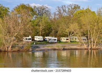 Mannheim, Germany - April 2022: Caravans and camper vans parked in a camp site on the bamks of the River Rhine at dusk.
