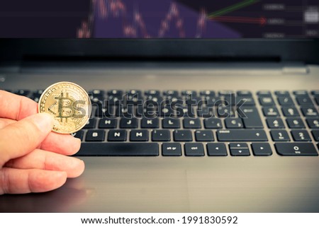 mano che tiene una moneta Bitcoin dorata su un computer portatile per analizzare il mercato delle criptovalute. Criptovaluta BTC. Valuta digitale. Stok fotoğraf © 