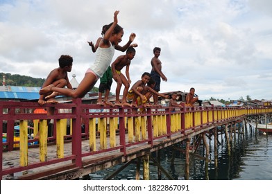 Manokwari, Papua, Indonesia - March, 2020: Papua children playing jumping and swimming in the water in Manokwari, Papua. They live near the ocean. It is simply happiness and togetherness.
