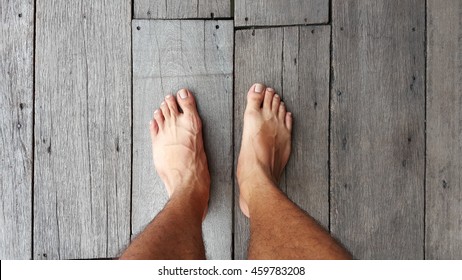 Man's Bare Feet On A Natural Wood Floor