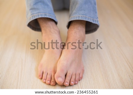 Mans bare feet on wooden floor in his new home