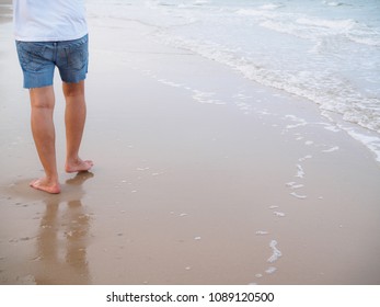 Man's Bare Feet Walking At A Beach