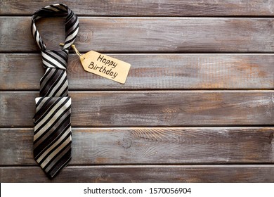 Man's Birthday Concept. Happy Birthday Text Near Male Tie On Dark Wooden Background Top View Copy Space