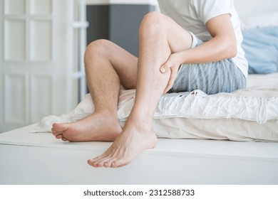 The man's calf muscle cramped, massage of male leg at home, painful area highlighted in red