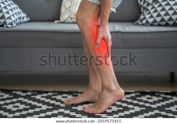The man\'s calf muscle cramped,\
massage of male leg at home, painful area highlighted in\
red