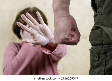 A man's clenched fist threatening with blurred view of unhappy crying woman raised her hand to protect her face on the background. domestic violence concept