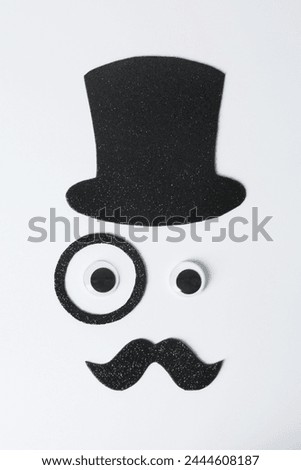 Man's face made of fake mustache, hat, eyes and monocle on white background, top view