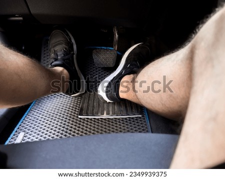 A man's feet put the pedals of the car controls 