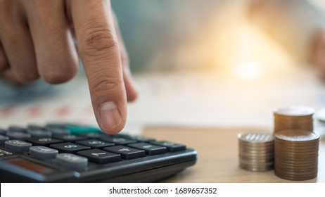 El dedo del hombre que presiona a la calculadora para calcular y analizar los ingresos y gastos el crecimiento de las monedas y los costos financieros, prudente y prudentemente, el concepto de inversión, ahorro y deuda