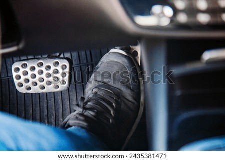 A man's foot in black sneaker on the floor in a car pressing gas pedal, carefully driving car concept