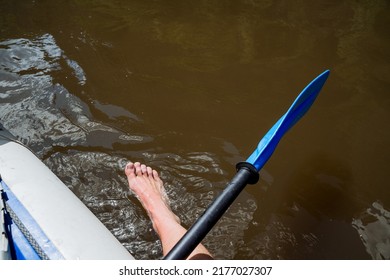 A man's foot sticks out in the water, a paddle for kayaking, a man rafting a canoe on a mountain river, water sports, a summer vacation on the water. High quality photo