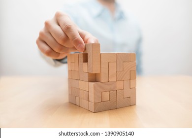 Man's hand adding the last missing wooden block into place. Business success concept. 