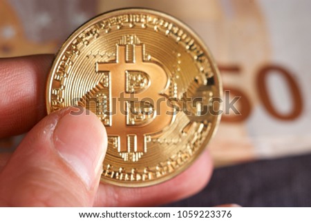 Man's hand with bitcoin and 50 fifty euros of backgrounds bills banknotes Macro