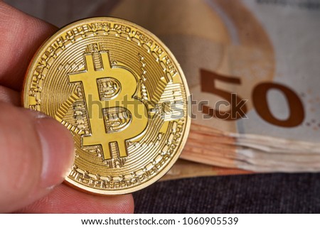 Man's hand with bitcoin and 50 fifty euros of backgrounds bills banknotes. Macro