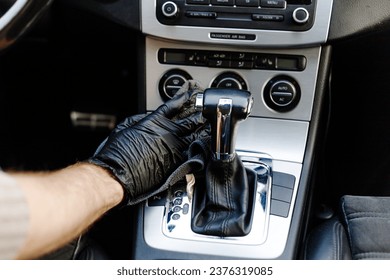 Man's hand in black glove cleaning car interior, dashboard and leather seats with microfiber cloth. Hand wipe down suede leather seat saloon interior. Car detailing - Shutterstock ID 2376319085