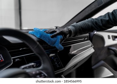 a man's hand in a black glove wipes the dashboard of a car - Shutterstock ID 1854566995