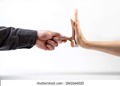 A man's hand in a black shirt gives a stack of money to a woman's hand, which refuses. Side view. White background. The concept of the world anti-corruption day