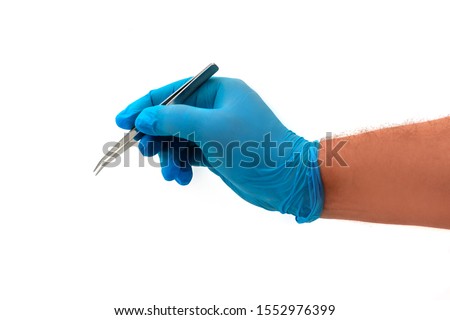 Man's hand in blue latex glove holding stainless medical tweezers isolated on white background. Operative surgery concept. Plastic and cosmetic surgery medical topic ストックフォト © 