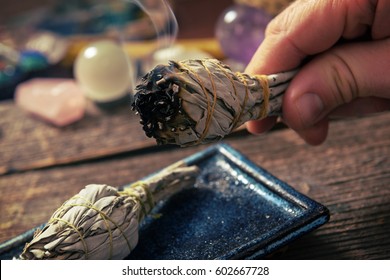 Man's hand with burning natural white sage incense