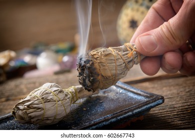 Man's hand with burning natural white sage incense