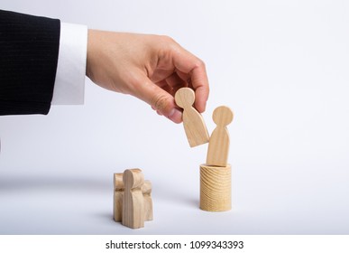The man's hand of a businessman in a business suit holds a wooden figure of a man in his hand and moves another figure from his post. The concept of firing an employee, the replacement of staff - Shutterstock ID 1099343393