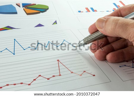 a man's hand is calculating the financial situation by means of graphs as used on the stock exchange