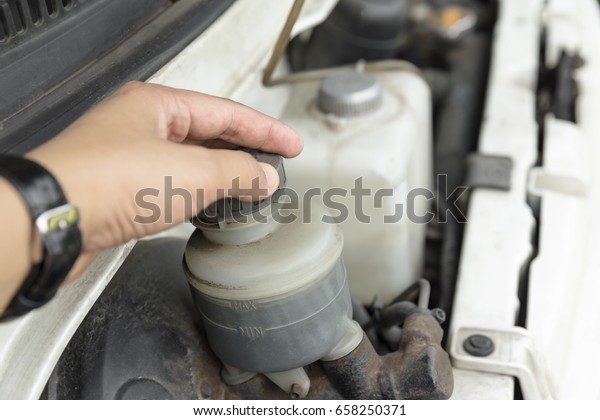 man\'s hand checking level of brake fluid tank\
- Car maintenance