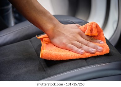 Man's Hand Cleaning Car Interior In Luxury Car With Microfiber Cloth. Hand Wipe Down Suede Leather Seat Of Sports Sedan.  Interior Car Detail & Leather Seat Repair Background. Car Wash & Clean Concept