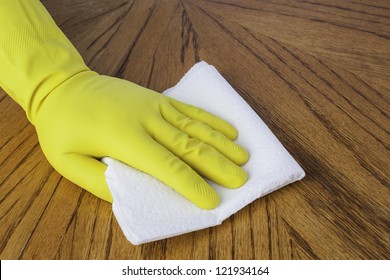 Mans Hand In Cleaning Glove Using A Paper Towel On A Wood Surface