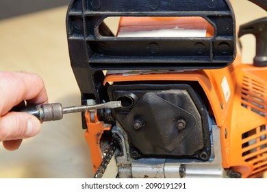 A man's hand cleans the exhaust pipe of a chain saw exhauster silencer with a screwdriver closeup - power tools equipment service, cleaning the exhaust system of a two-stroke engine from carbon snuff