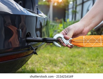 A man's hand clings a tow rope to a tow hook in a passenger car, close-up - Shutterstock ID 2116216169