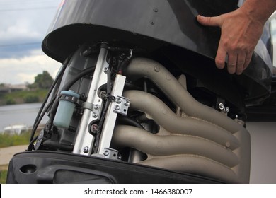 A Man's Hand Closes The Hood Of A Powerful Outboard Boat Motor, Repair And Maintenance Of Boat Engines, A View Of The Intake Manifold Of A Four-cylinder Four-stroke Injector Motor