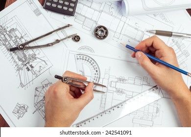 Man's hand with a compass. Mechanical engineer at work. Technical drawings. Pencil, compass, calculator and hand man. Paper with technical drawings and diagrams. 