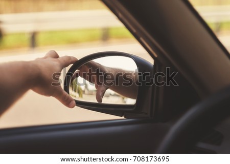 man's hand corrects the side mirror in the car, retro toning.