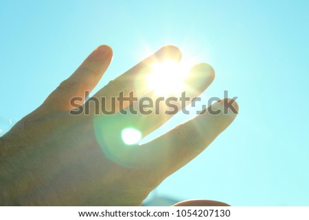 A man's hand covering the sunlight. The sun shines through the hand. Background.